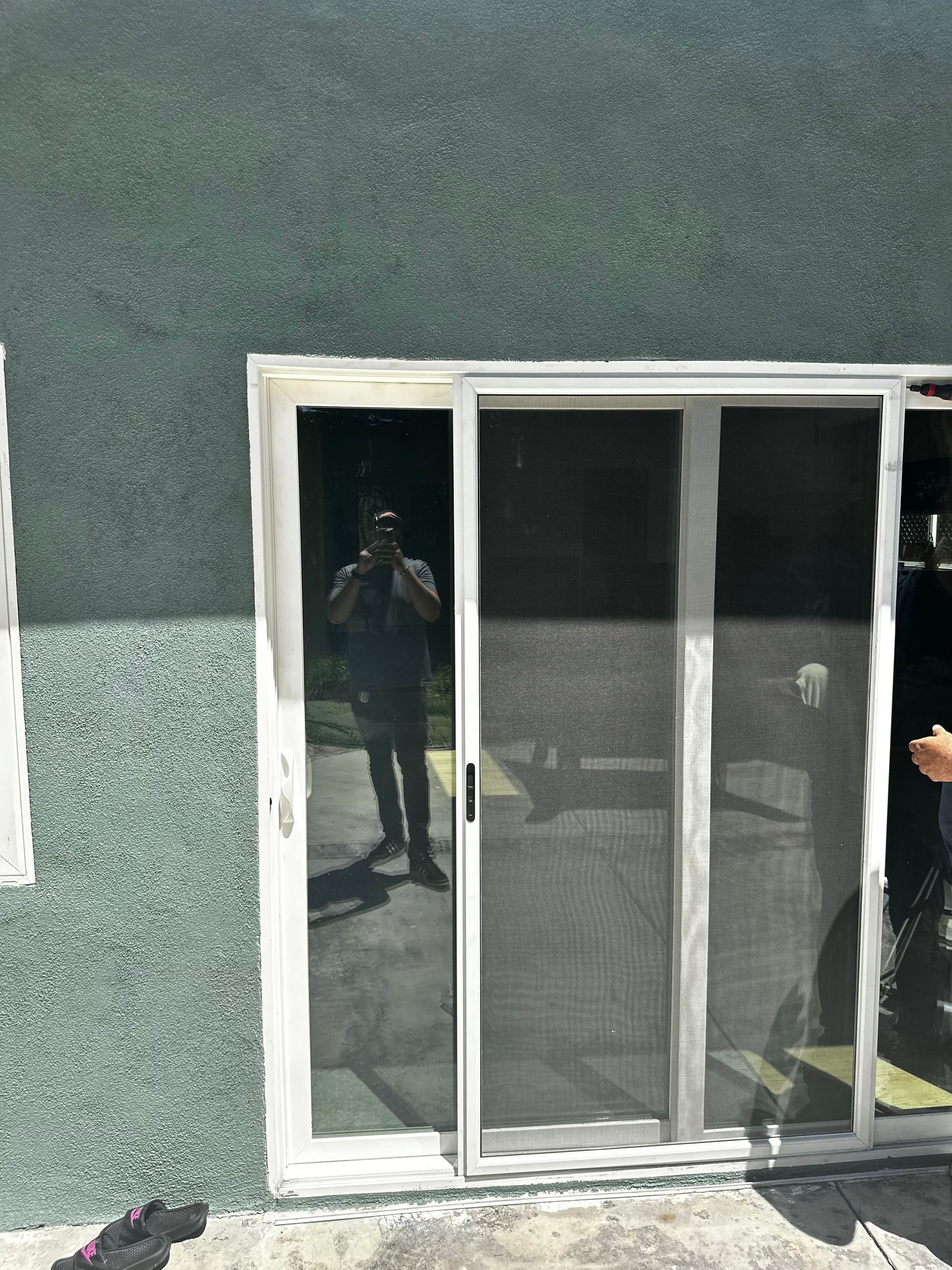 A man is taking a picture of himself in a sliding glass door.