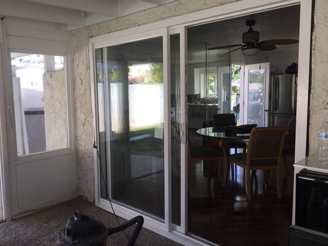 A sliding glass door is open to a dining room with a table and chairs.