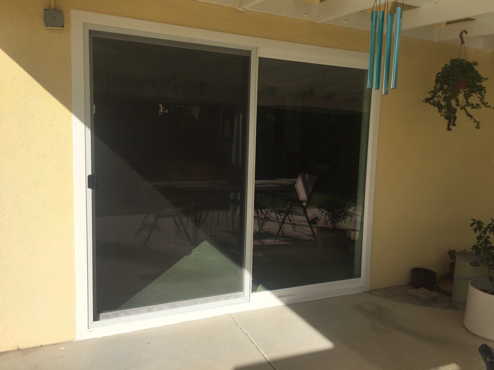 A patio with a sliding glass door and a wind chime hanging from the ceiling.