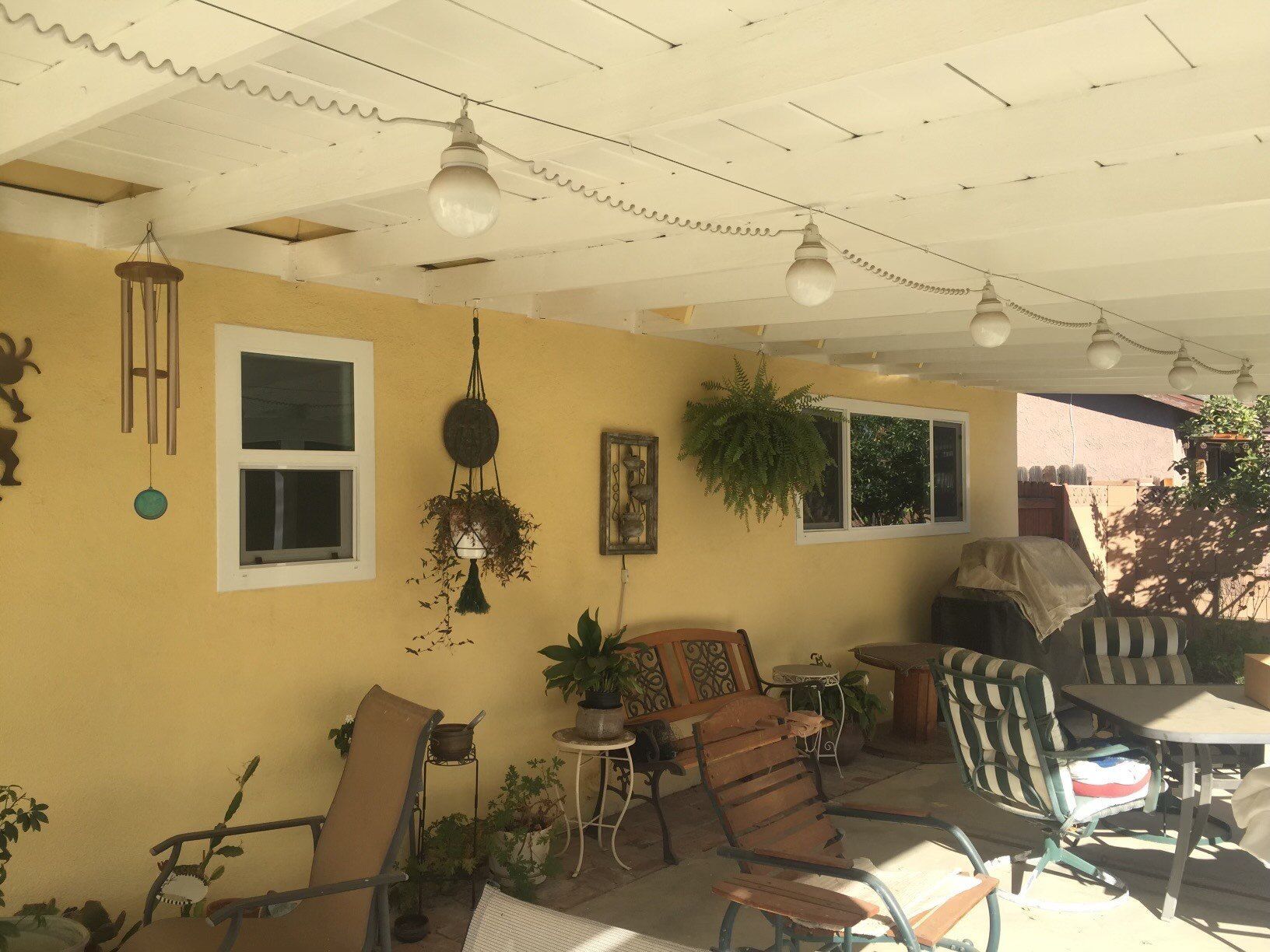 A yellow house with a patio area with chairs and tables