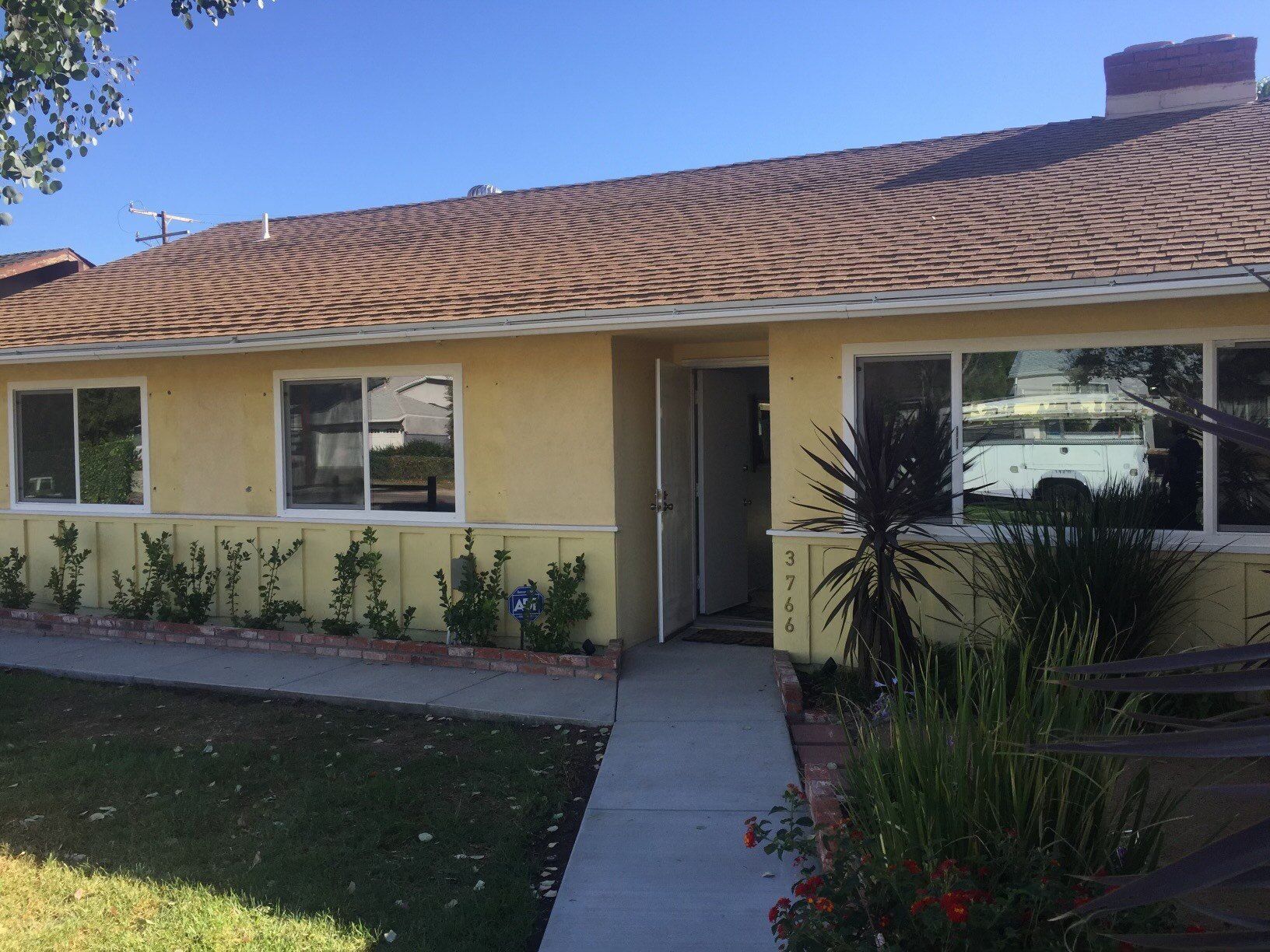 A yellow house with a brown roof and many windows