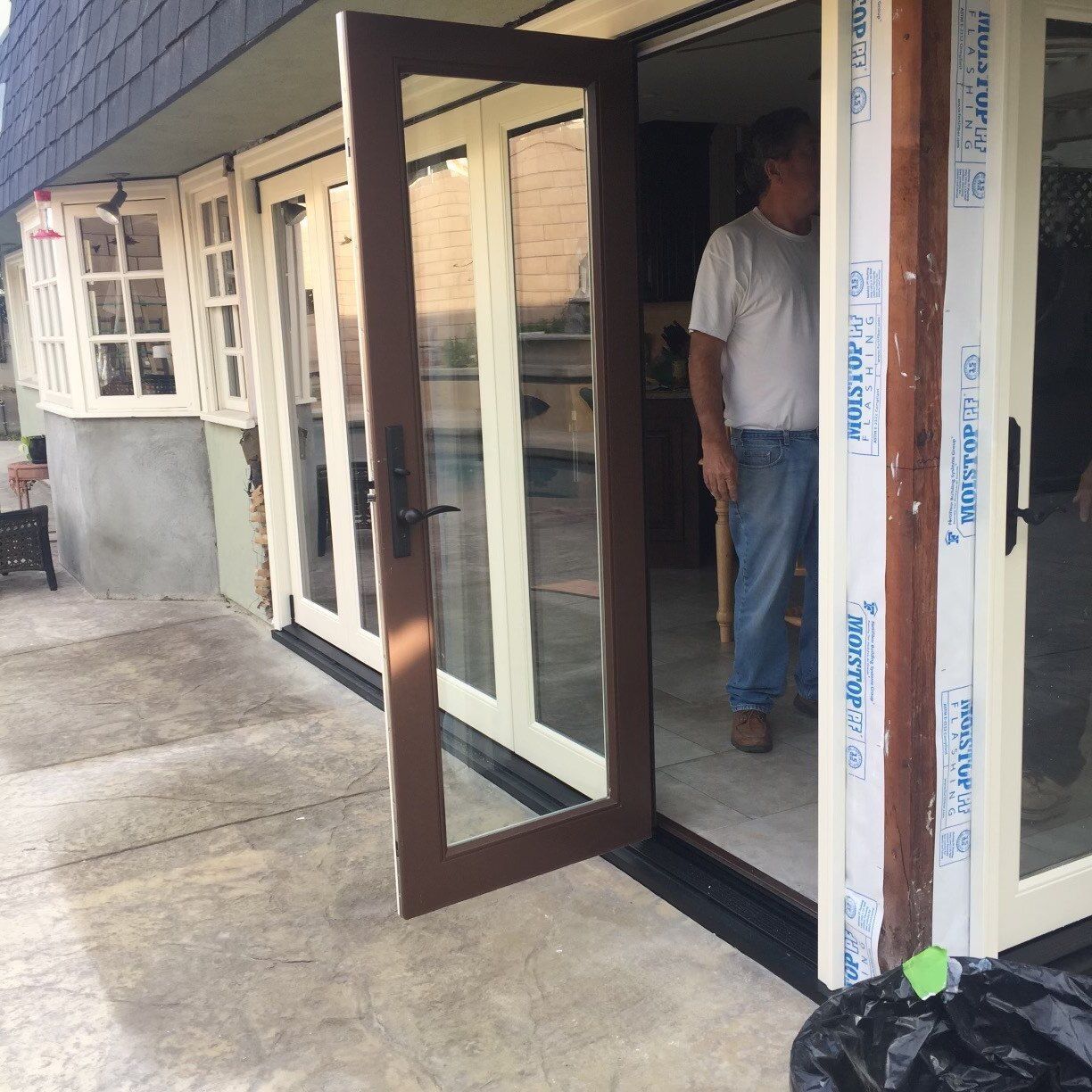 A man in a white shirt is standing in front of a sliding glass door