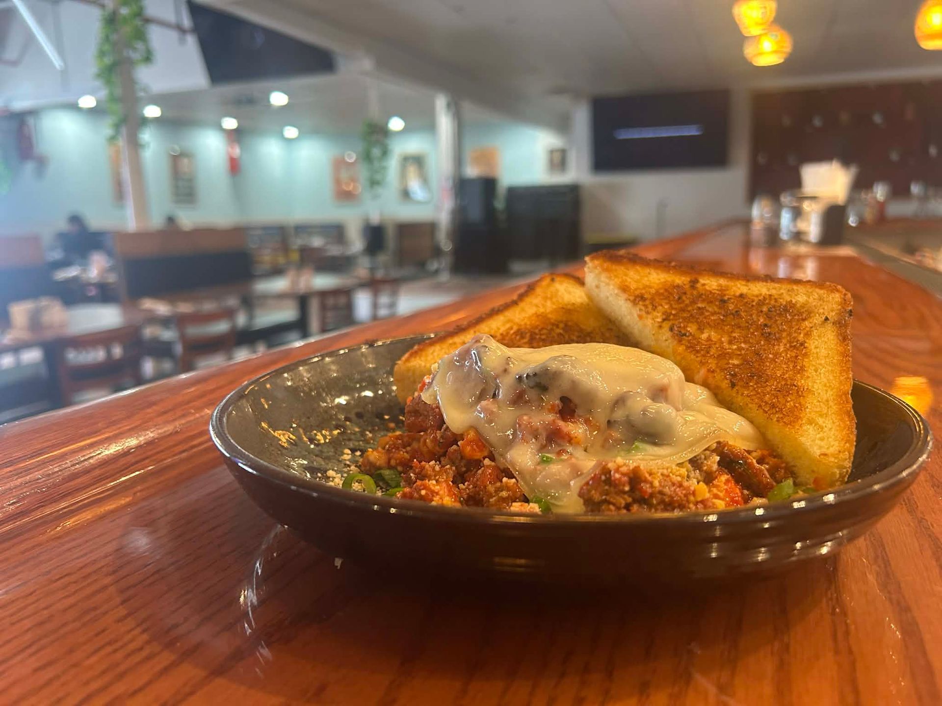Plate with grilled chicken, fettuccine alfredo, garlic toast, and tomato garnish.
