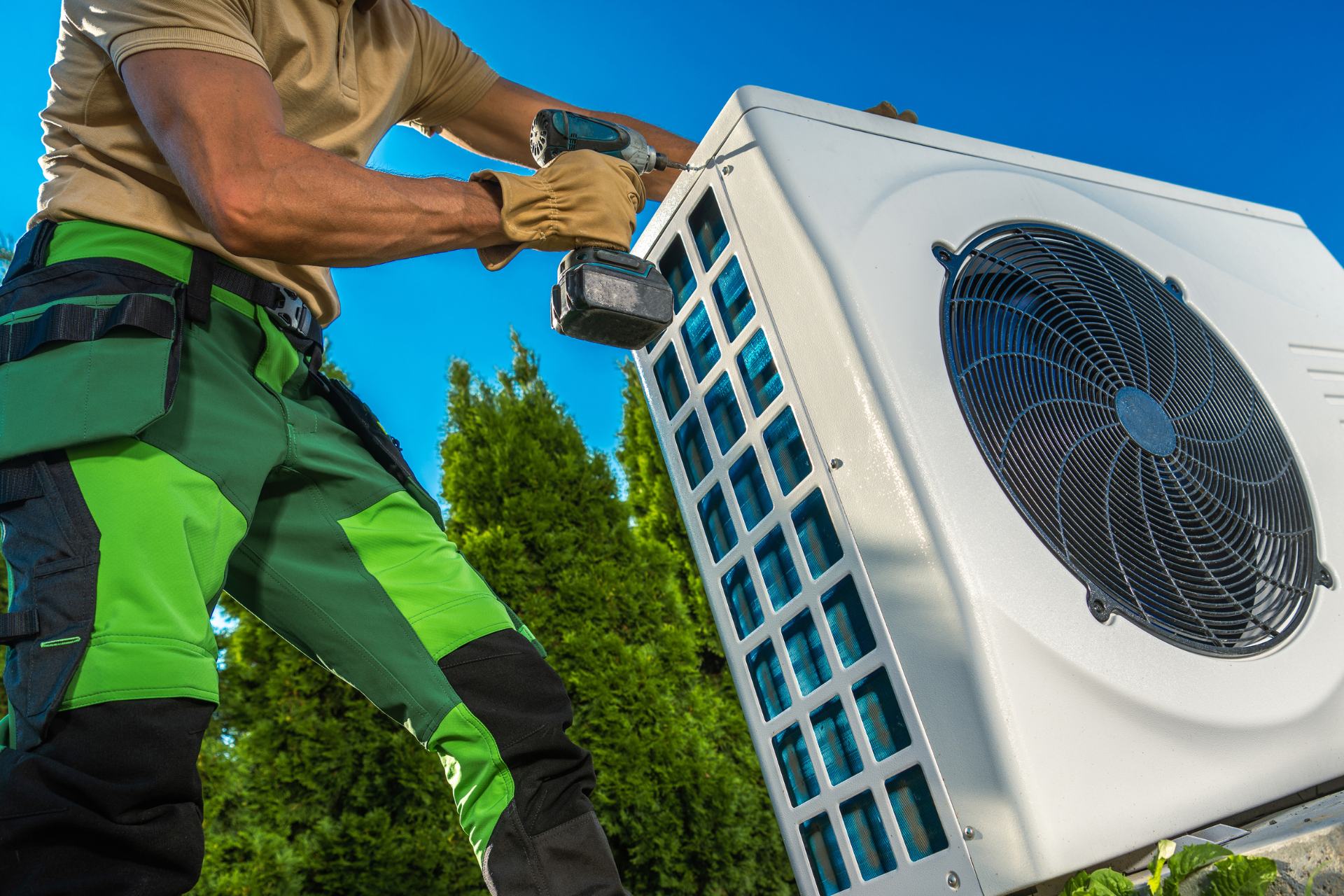 A man is working on an air conditioner with a drill.