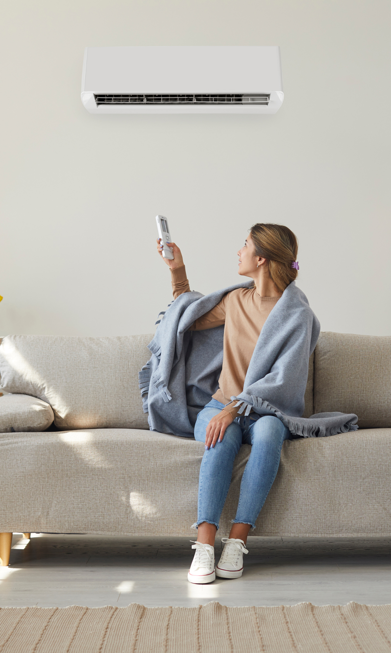 A woman is sitting on a couch holding a remote control.