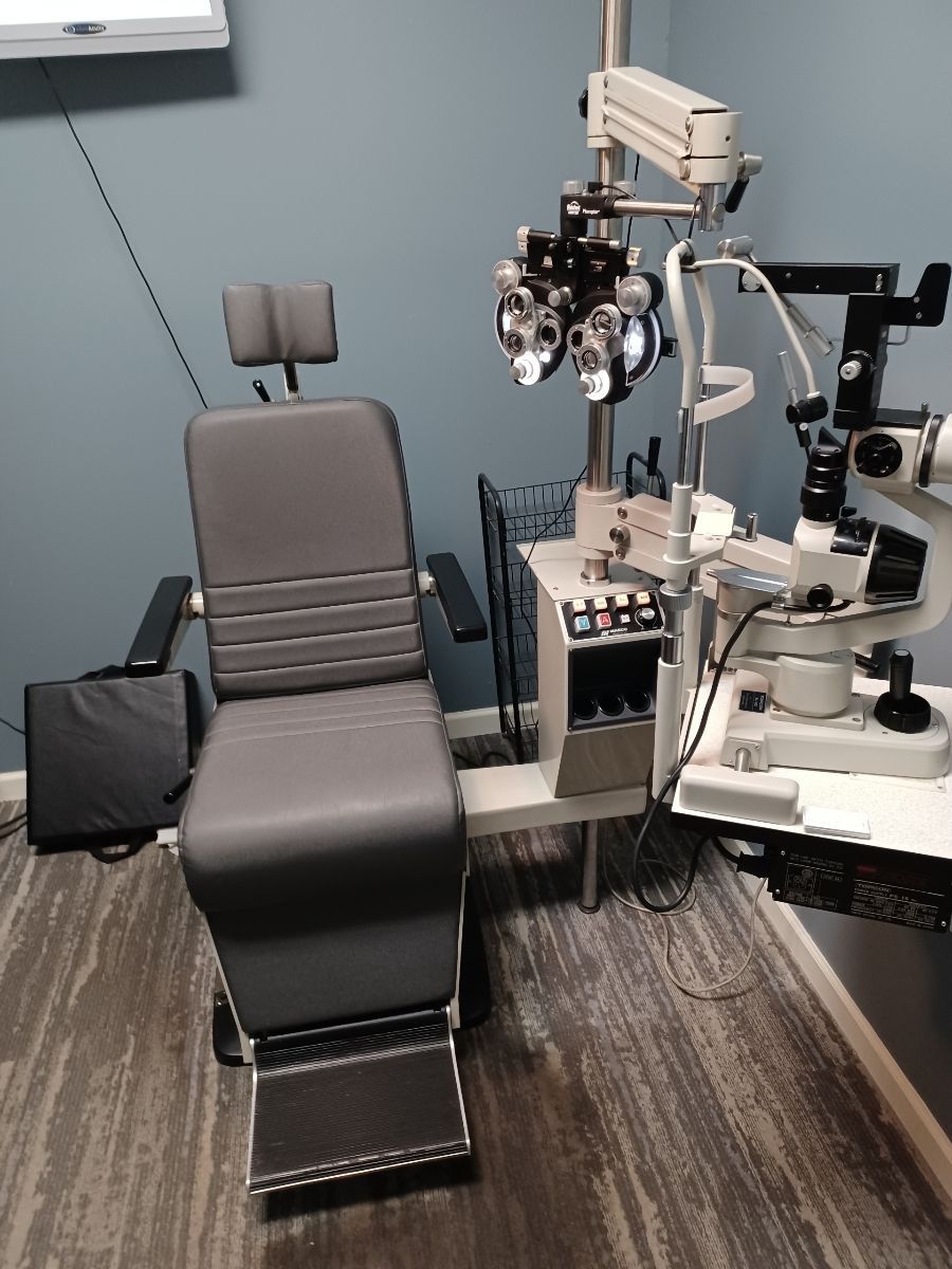 An ophthalmologist 's office with a chair and a microscope.