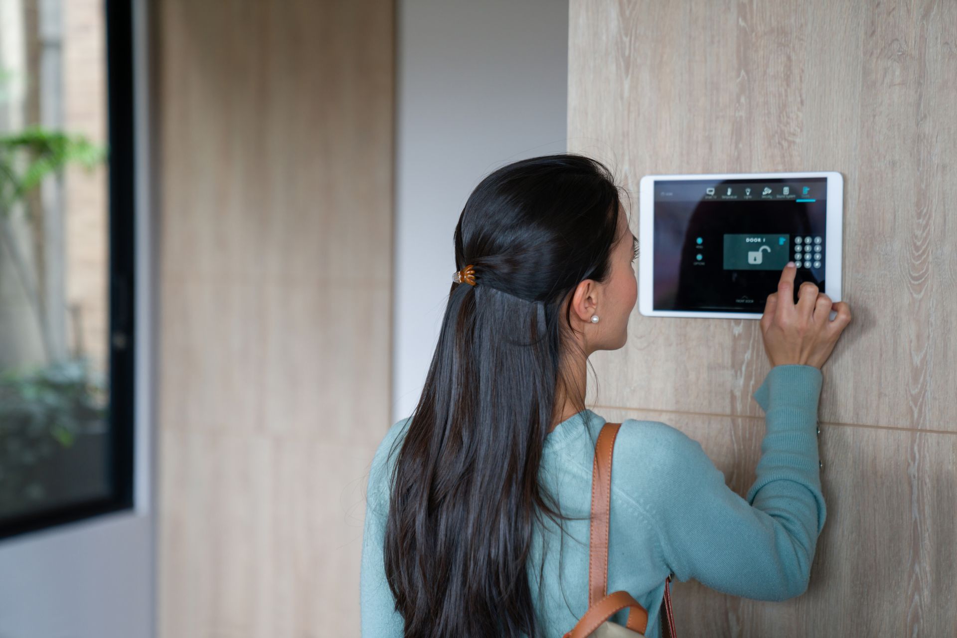 Woman entering pin to lock the door of her house - Wireless Security Alarm Systems In Brisbane