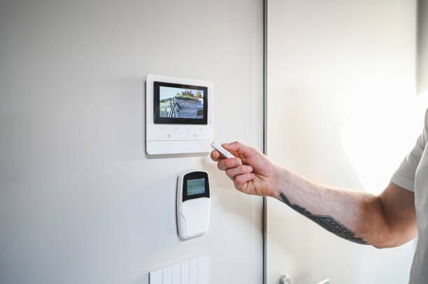 Wireless security alarm system being managed by a tattooed male, with a control in hands.