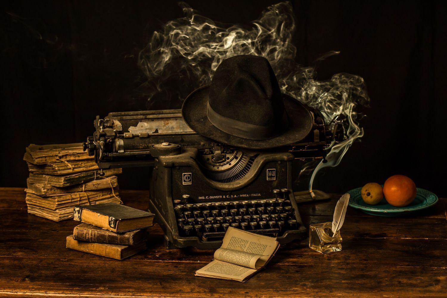 An old typewriter with a hat on top of it on a wooden table.