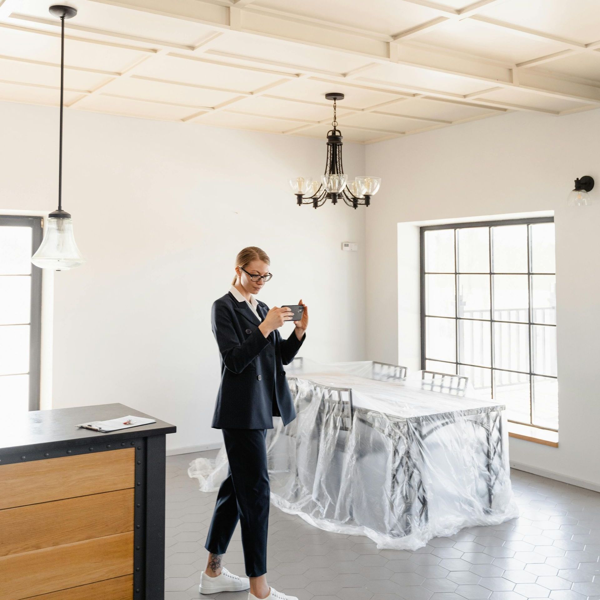 A man in a suit is taking a picture of a table wrapped in plastic.