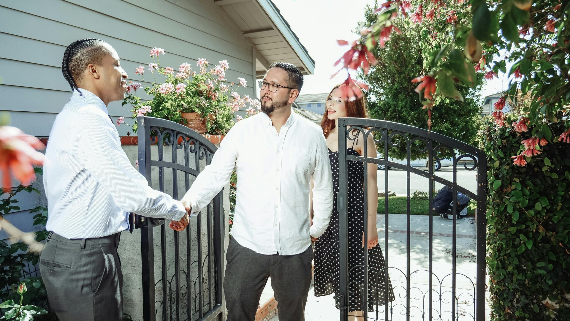 A man is shaking hands with a woman in front of a house.
