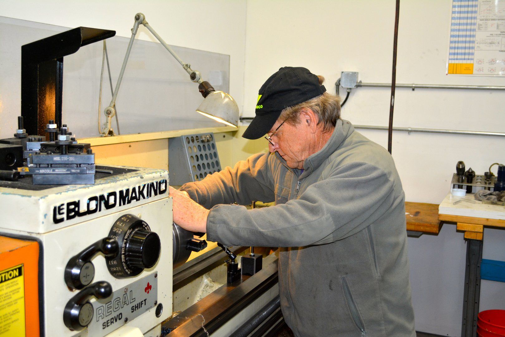 A man is working on a lathe in a workshop.