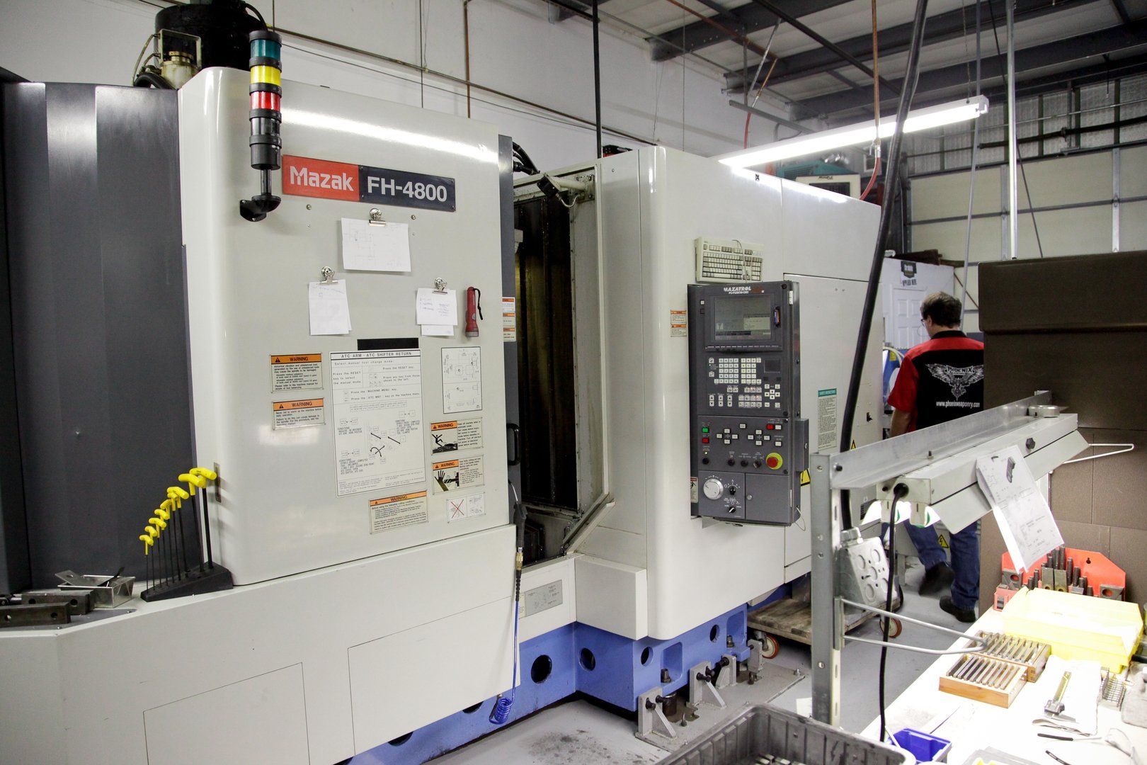A machine is sitting in a warehouse next to a conveyor belt.