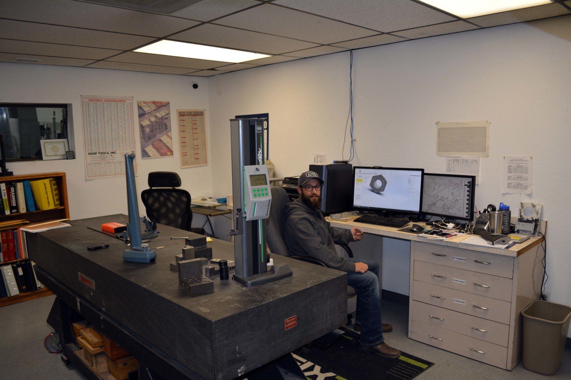 A man is sitting at a desk in a room with a computer.
