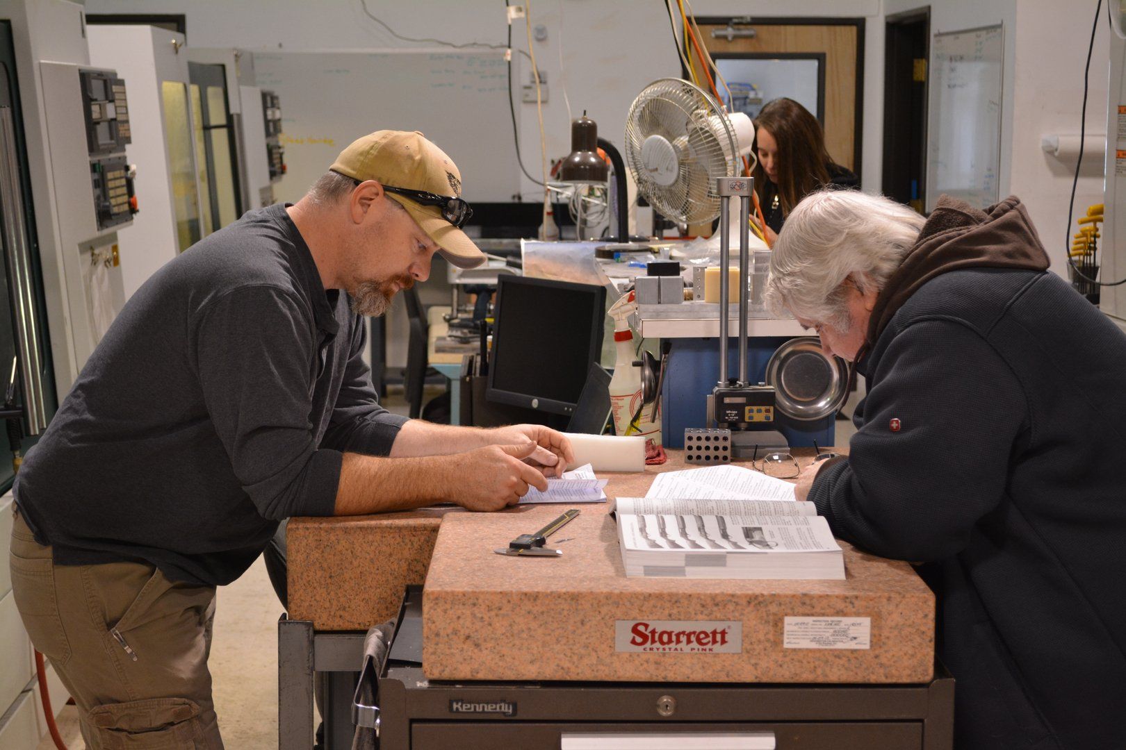 Two men are sitting at a table working on a piece of paper.