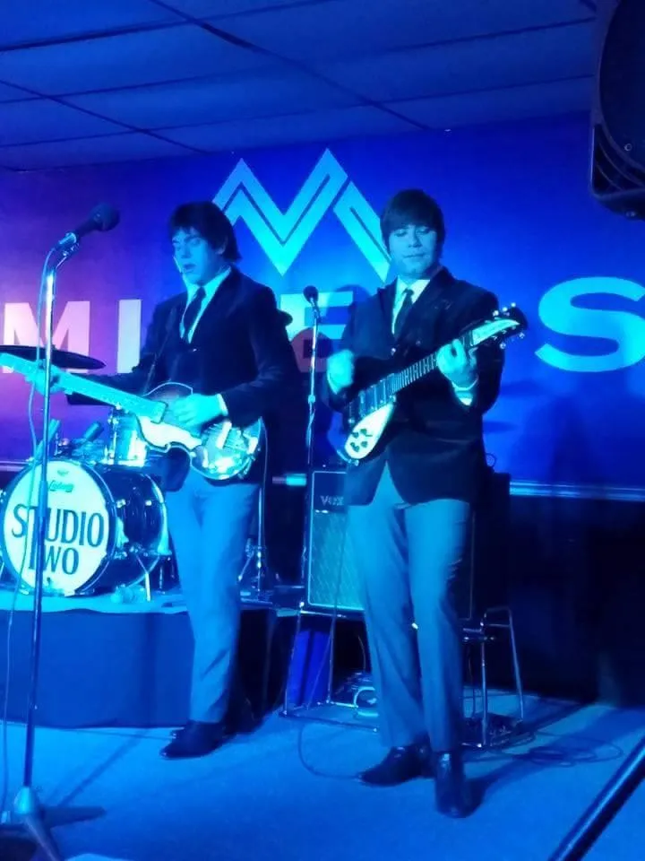 Two men playing guitars in front of a sign that says studio two