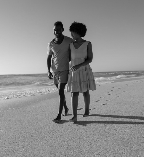 young couple walking on the beach together smiling