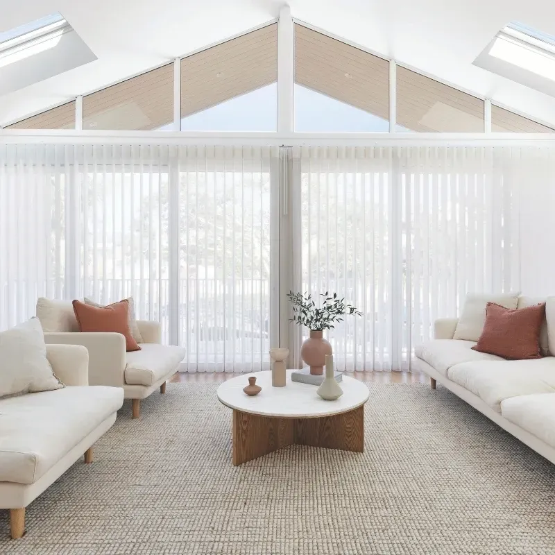 Living room with cream couches, beige rug, round coffee table, and large windows.