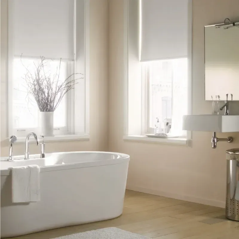 Bathroom with white tub, window, and sink. Natural light streams through the windows, illuminating the space.