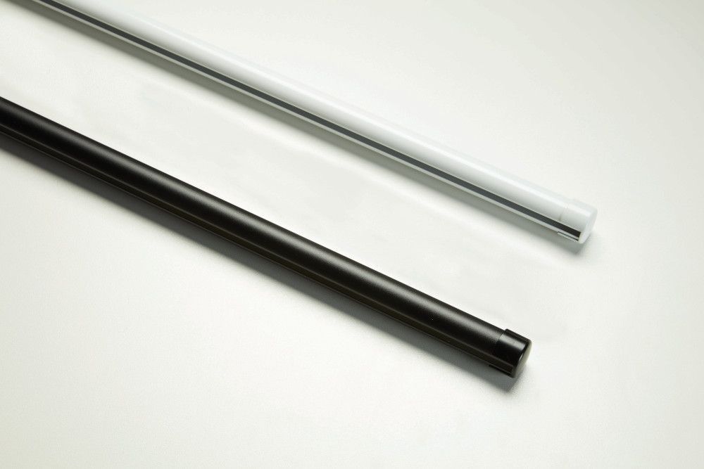 Two metal curtain rods, one black and one white, lying diagonally on a white surface.