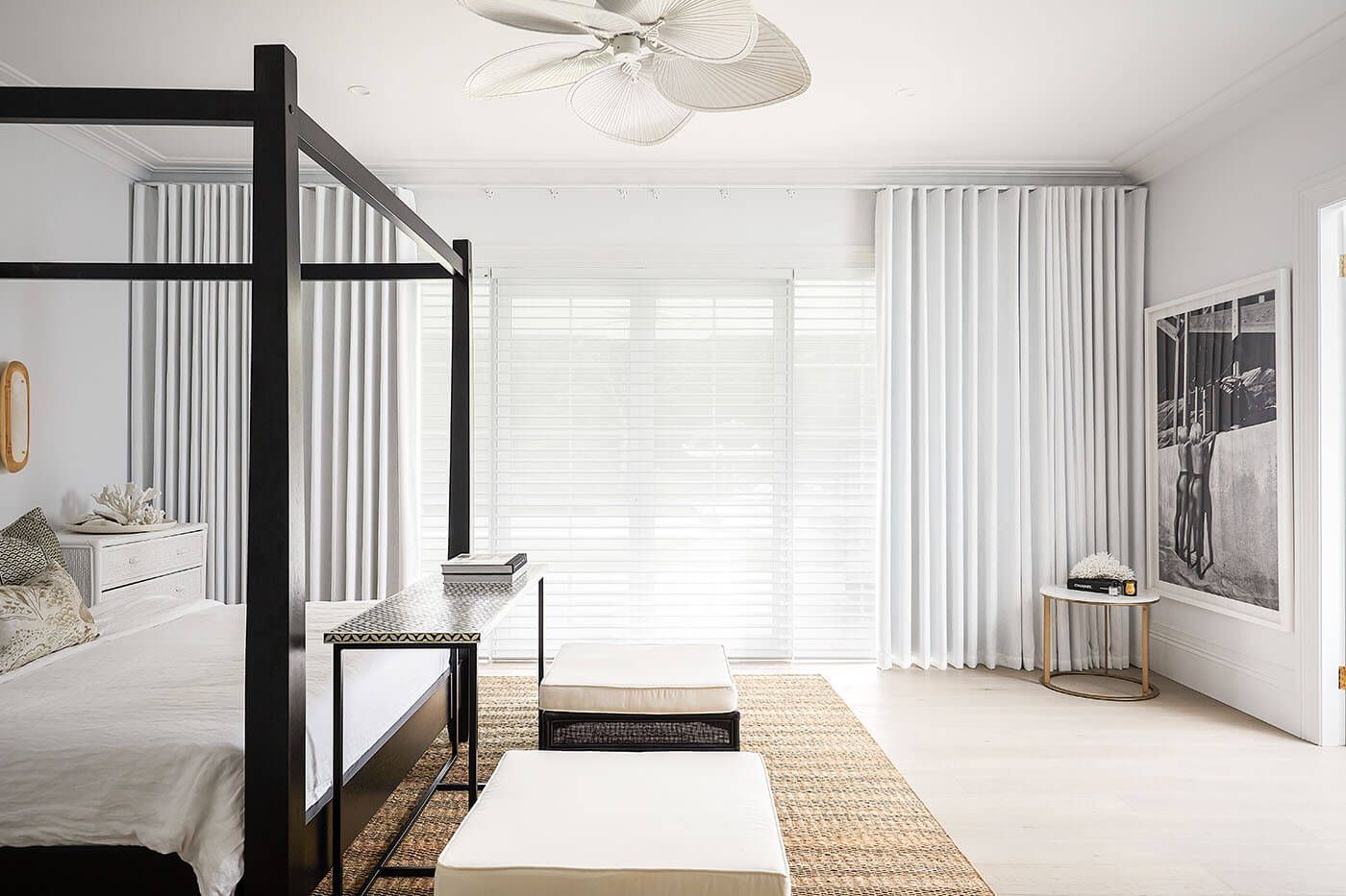 Bedroom with four-poster bed, white curtains, and neutral decor.