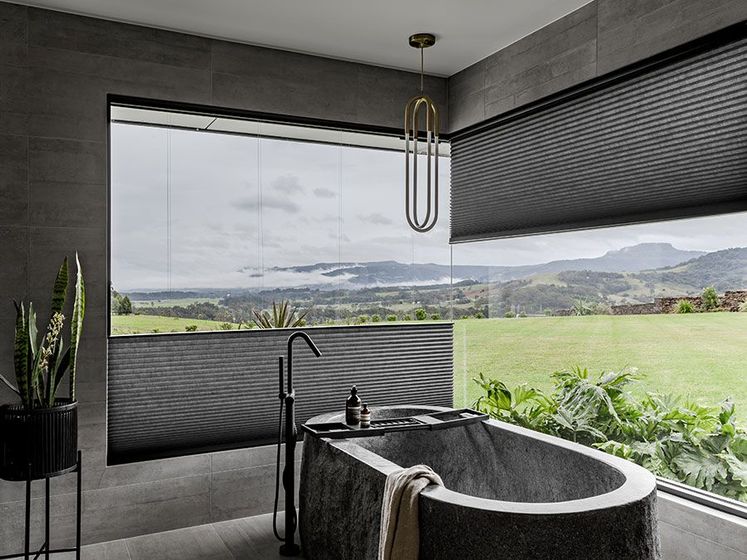 Luxurious bathroom with bathtub, window, and scenic mountain view.