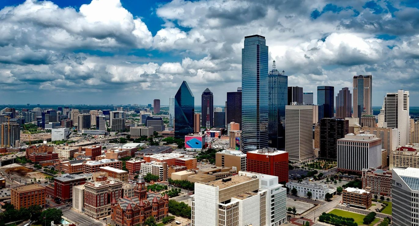 City skyline with modern high-rise buildings under dramatic clouds, viewed from above.