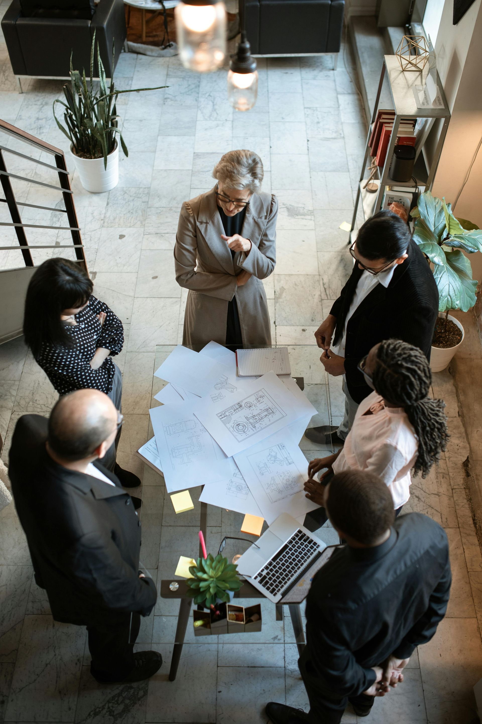 Group around a table reviewing papers and a laptop in a bright office workspace.
