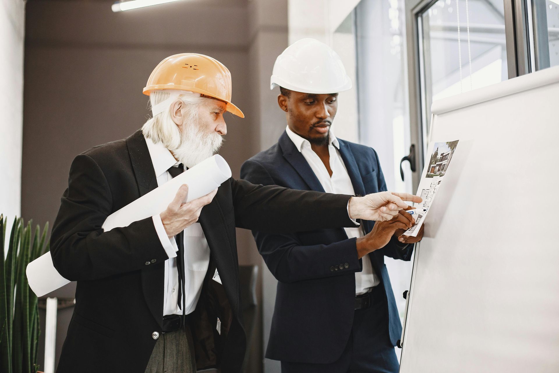 Two engineers in hard hats reviewing plans at a construction site