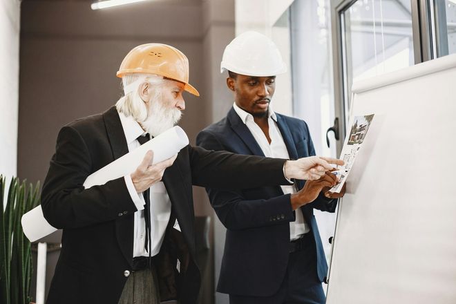 Two engineers in hard hats reviewing plans at a construction site