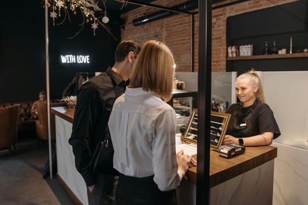 Two customers at a jewelry counter with a smiling clerk in a modern store