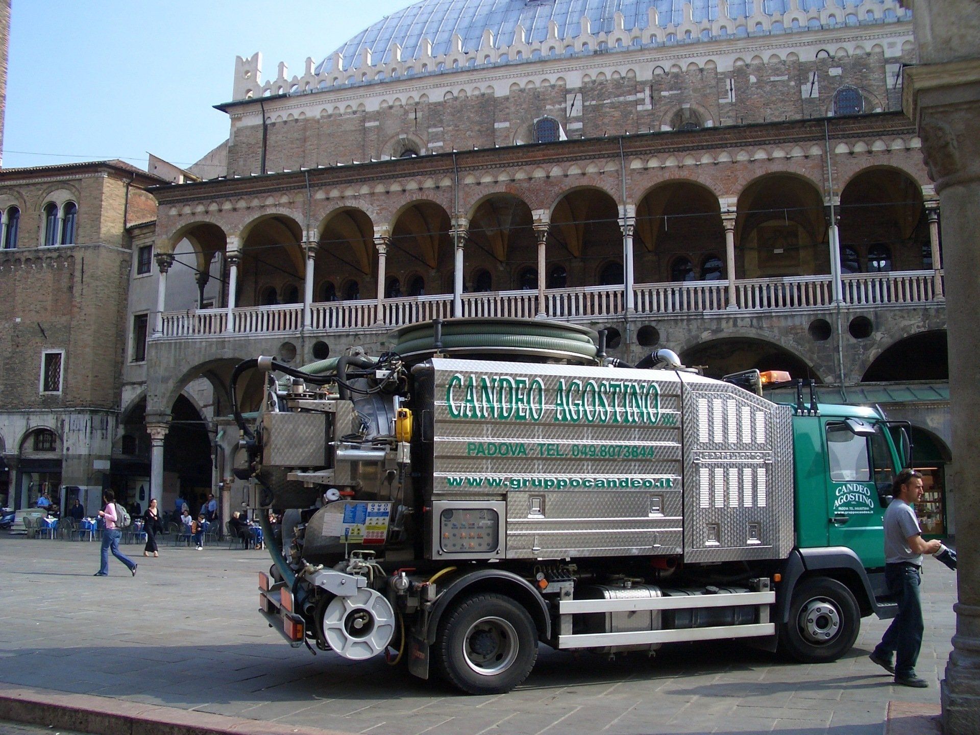 Un camion ecologico per la nettezza urbana parcheggiato davanti a un vecchio edificio con tetto a cupola, Italia.