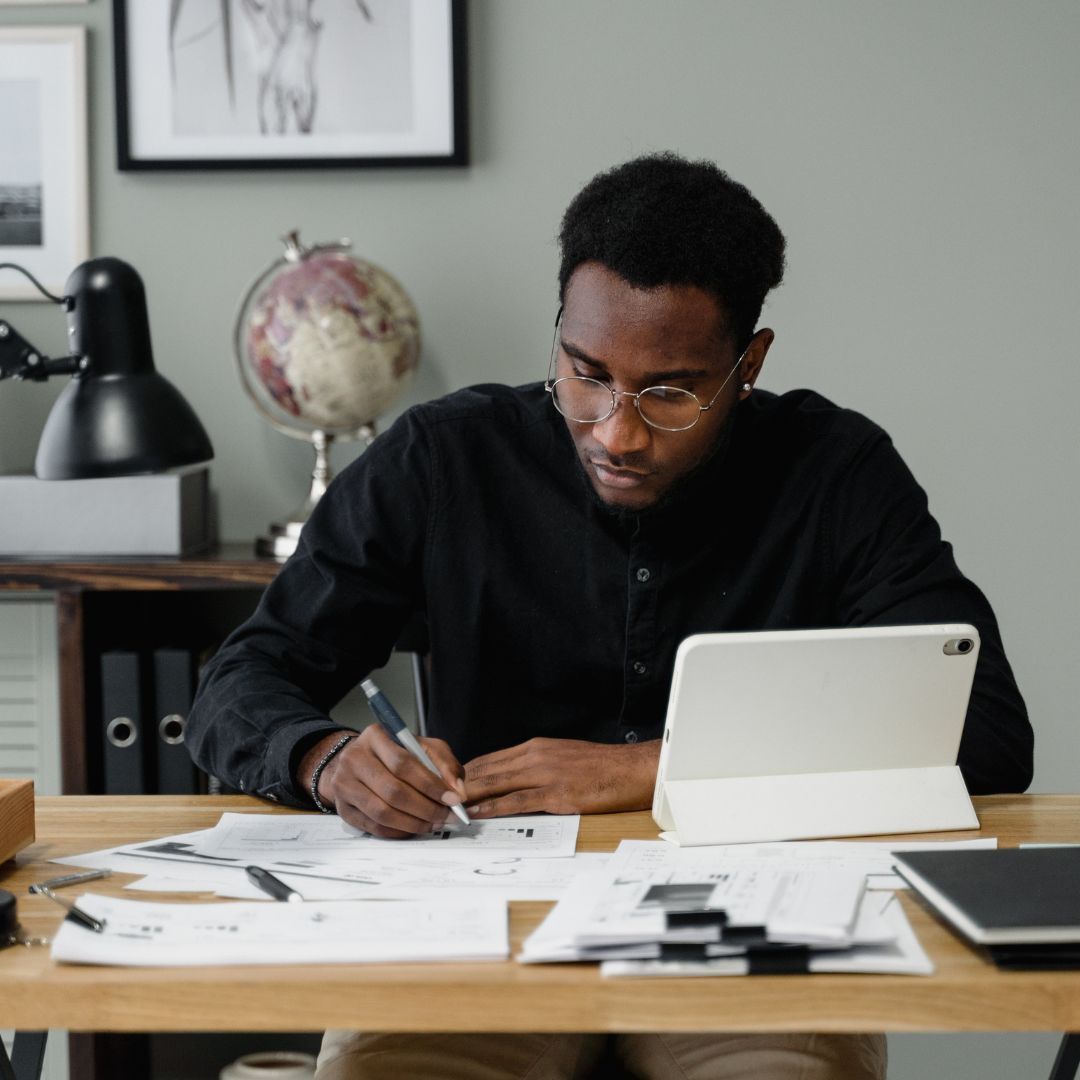 a man in a home office looking at paperwork and writing