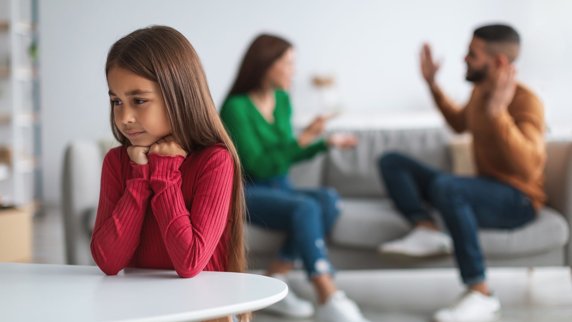 Child looking sad with parents fighting in the background