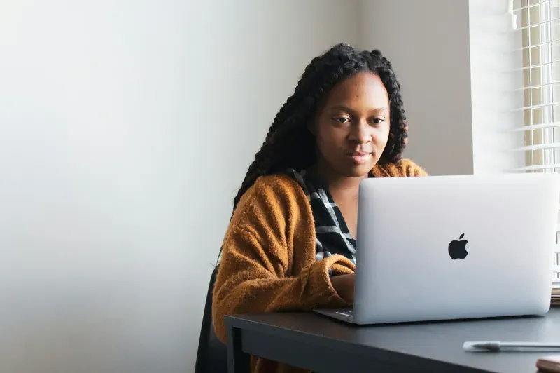 a woman sitting at a desk, looking at her laptop