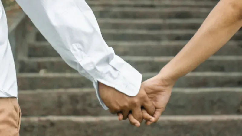 man and woman holding hands in front of a staircase
