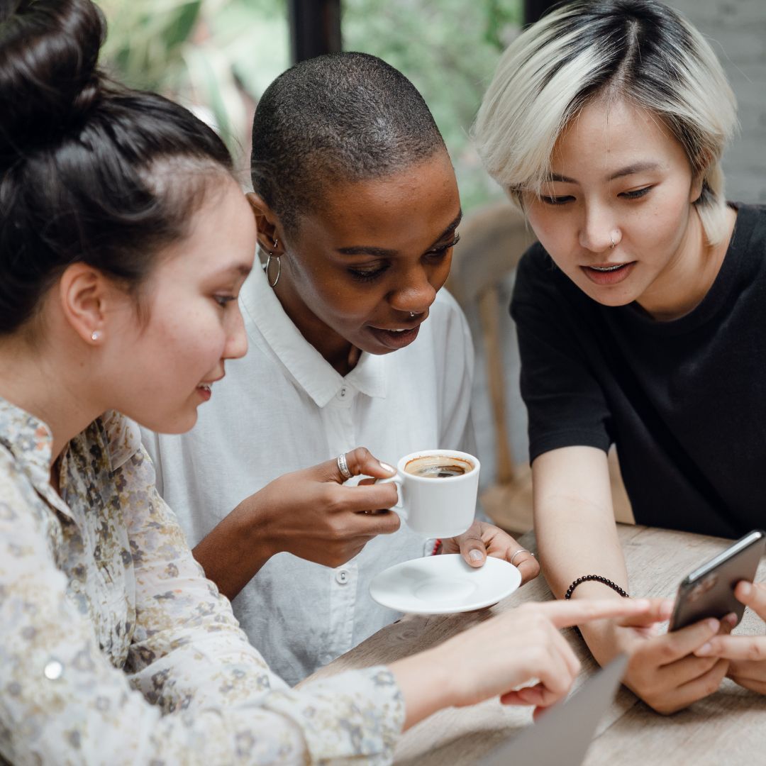 three woman looking at phone