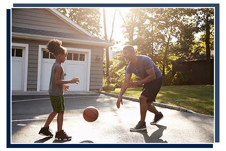 father and daughter playing basketball in driveway