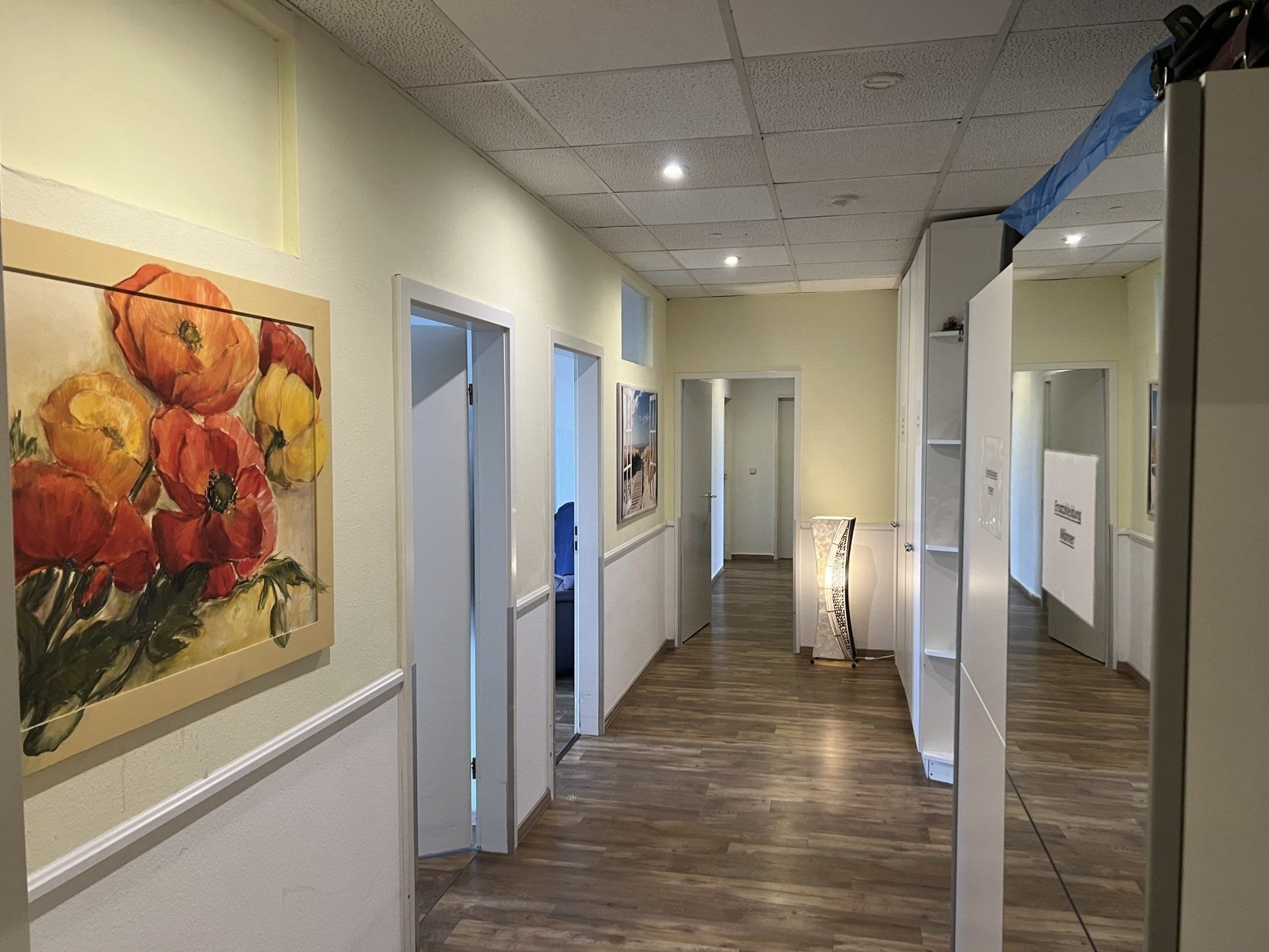 Ein langer Flur mit einem Blumengemälde an der Wand.