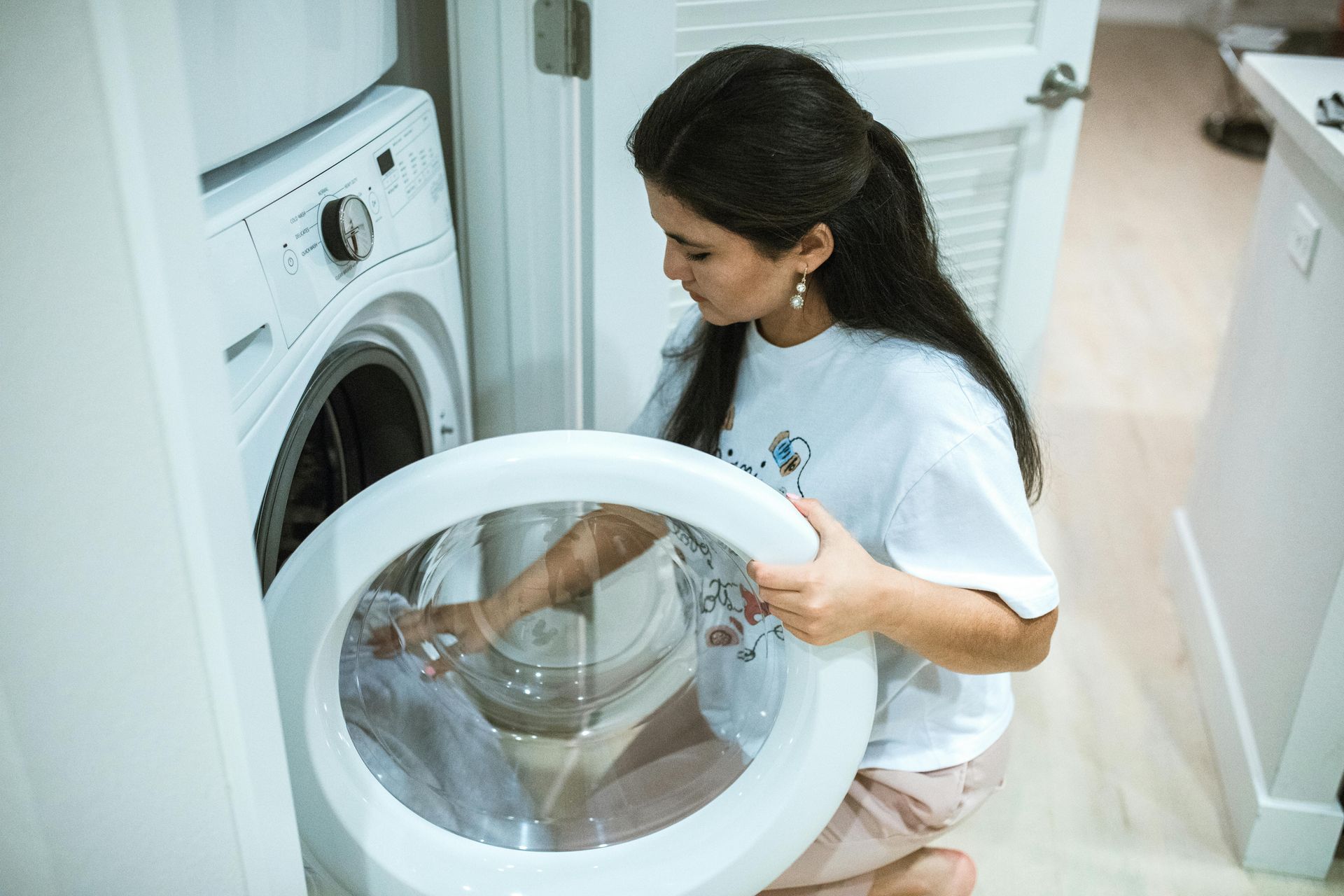 Eine Frau steckt Kleidung in eine Waschmaschine.