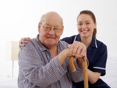 Eine Krankenschwester hilft einem älteren Mann mit seinem Gehstock.