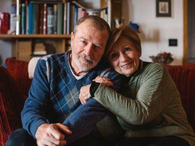 Ein Mann und eine Frau sitzen auf einem Sofa und umarmen sich.