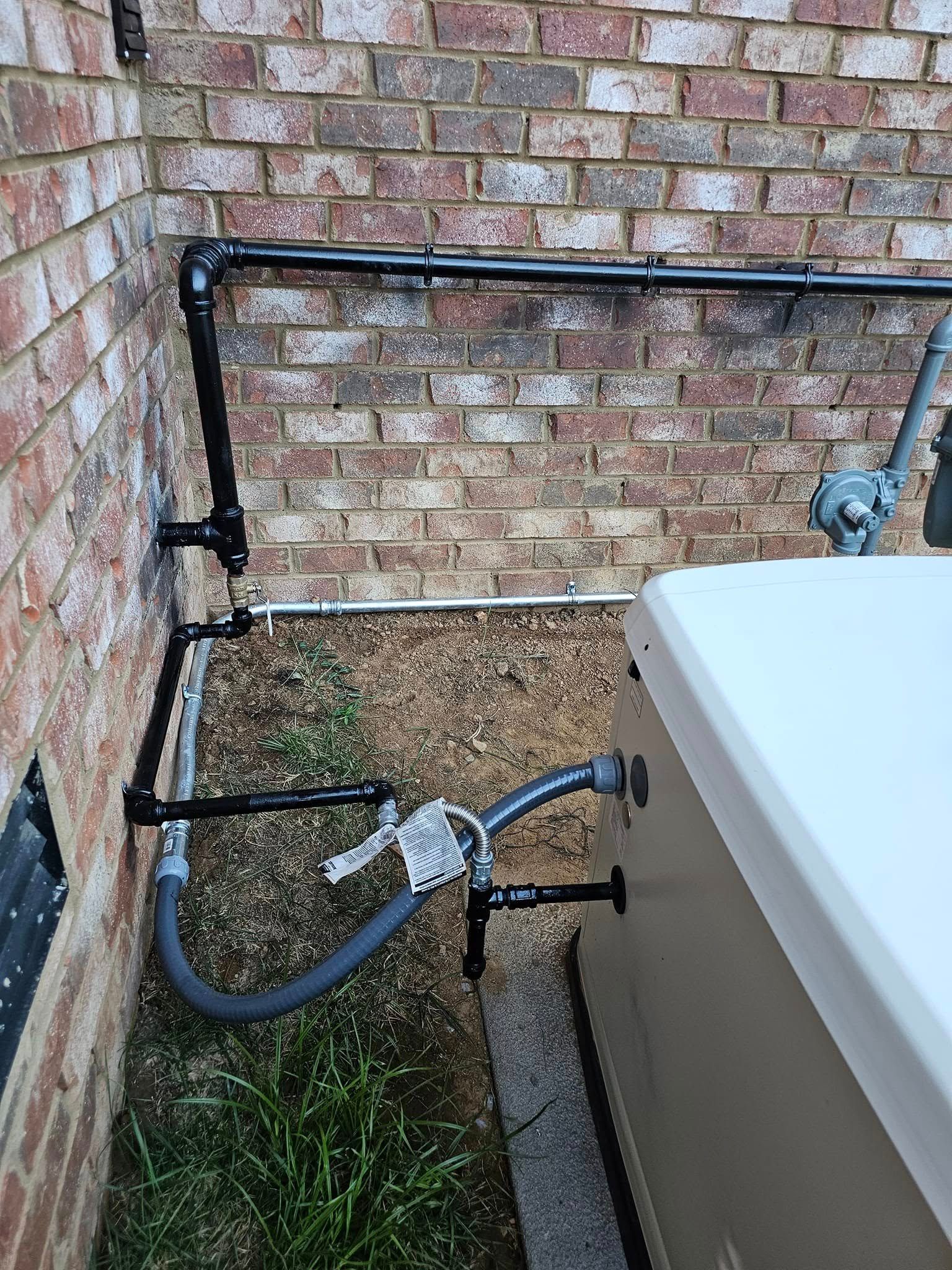 Black gas pipes run along a brick wall and connect to a beige generator unit.