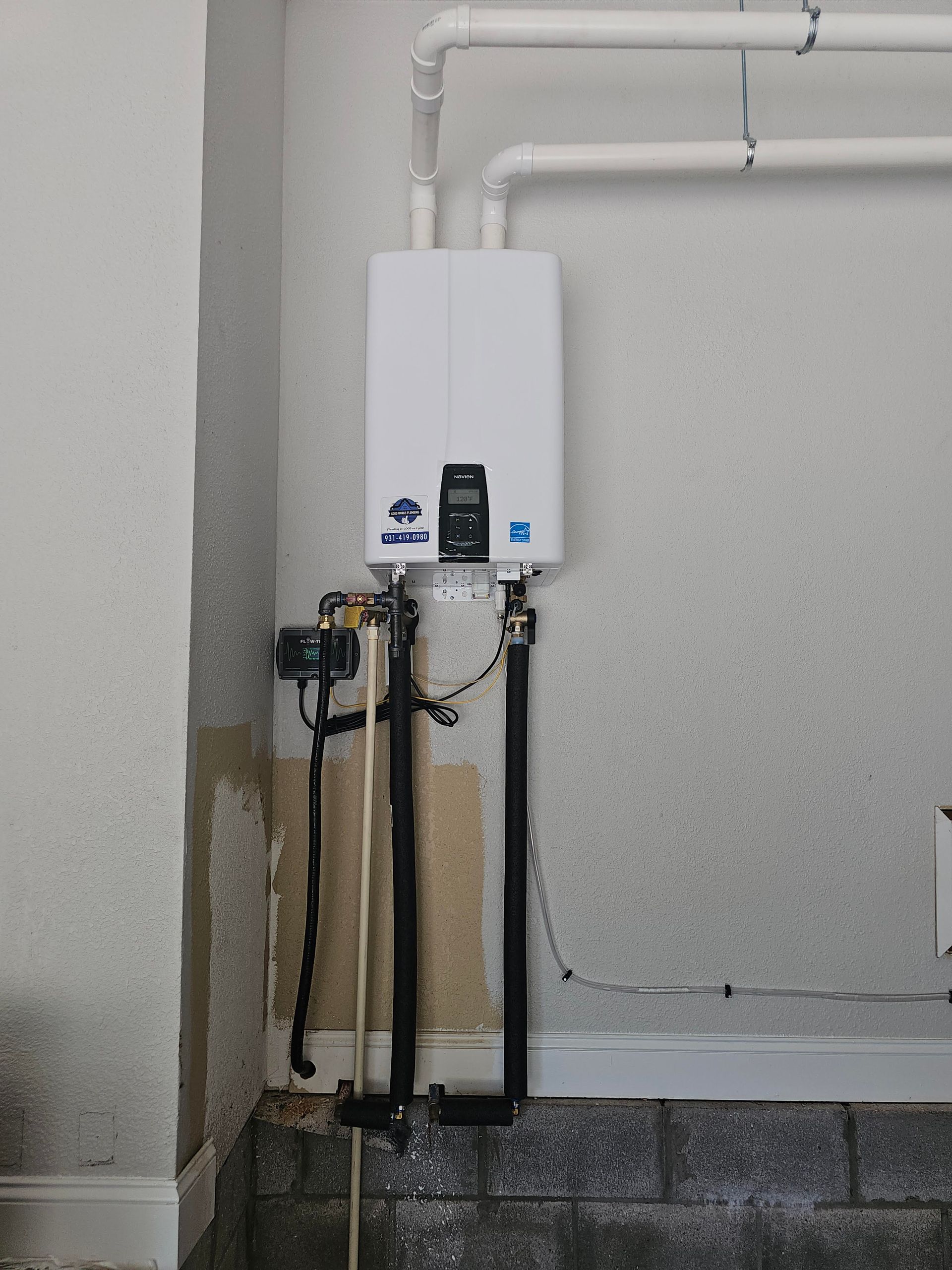 Tankless water heater installed on a basement wall with connected pipes.