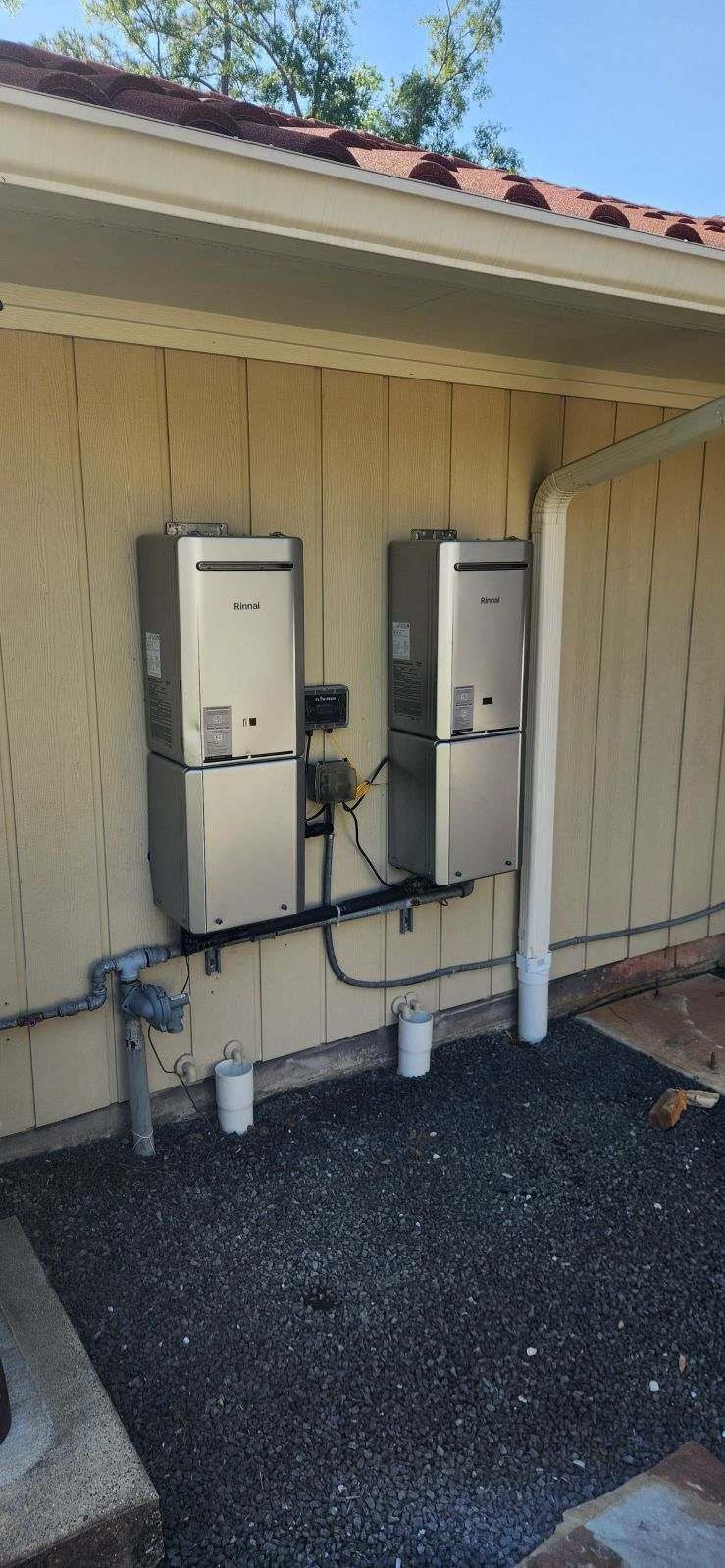 Black pipes on a white flat roof, supported by blocks. Houses are in the background.