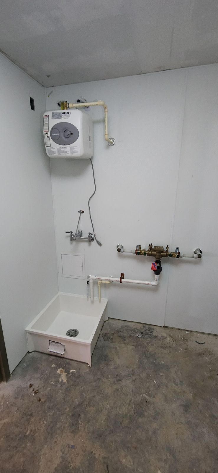 White water heater tank with plumbing in a utility room.