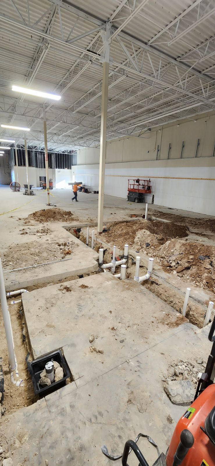 Interior construction site with plumbing and excavation in progress.