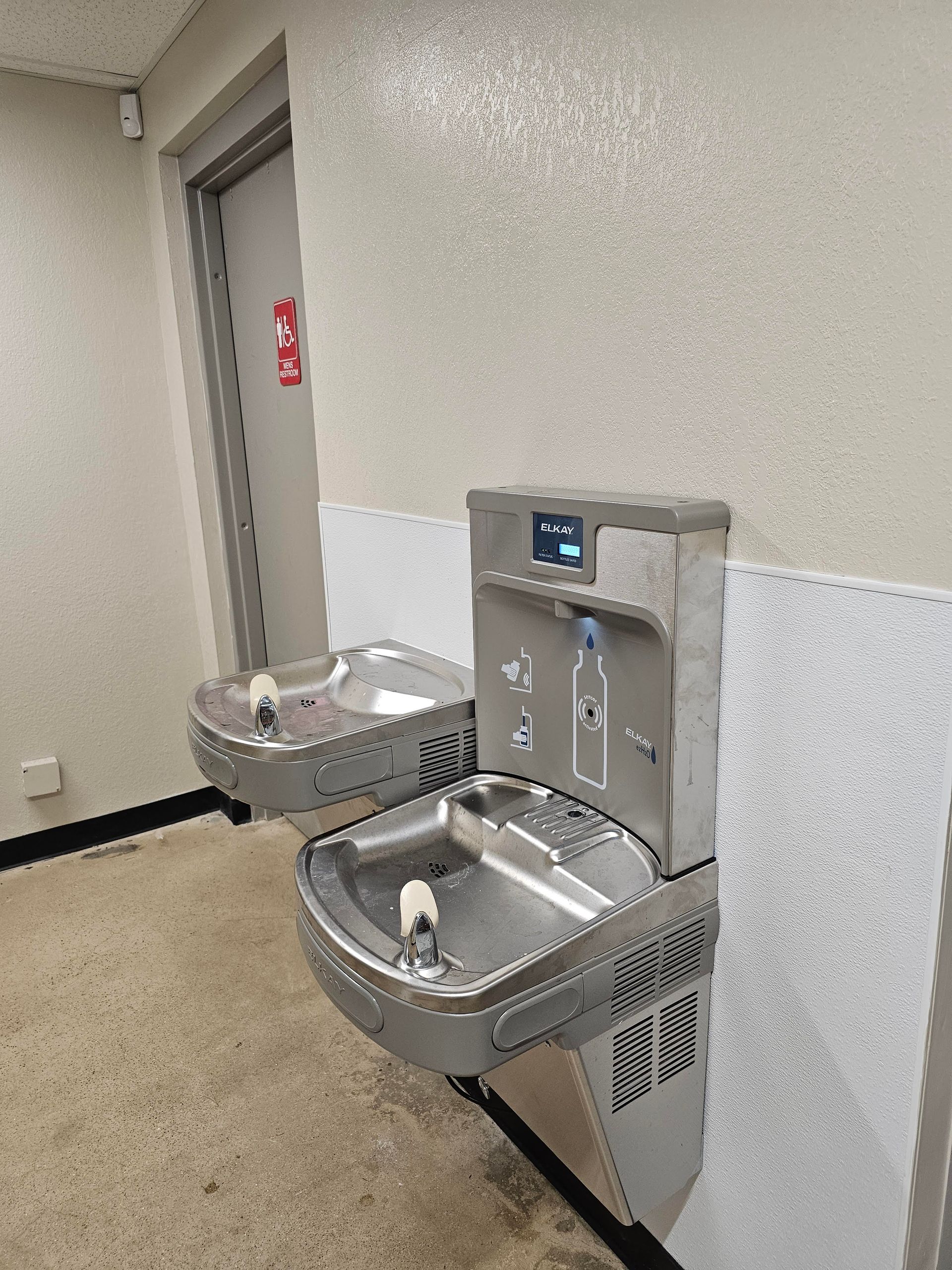 Person using a plunger in a sink filled with brown water, other tools and yellow gloves nearby.