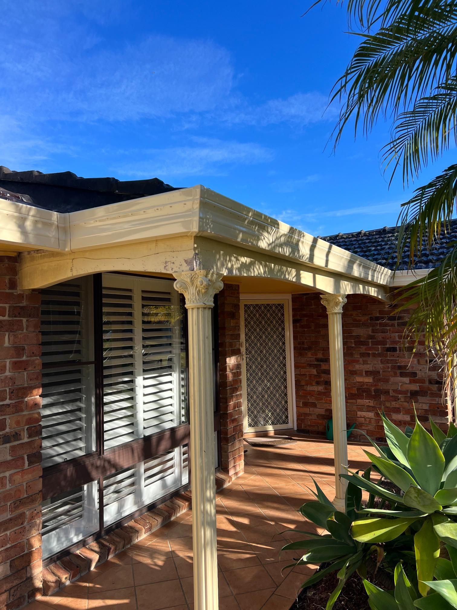 A Brick House With a Porch and Shutters on the Windows — Gutterworx in Wamberal, NSW