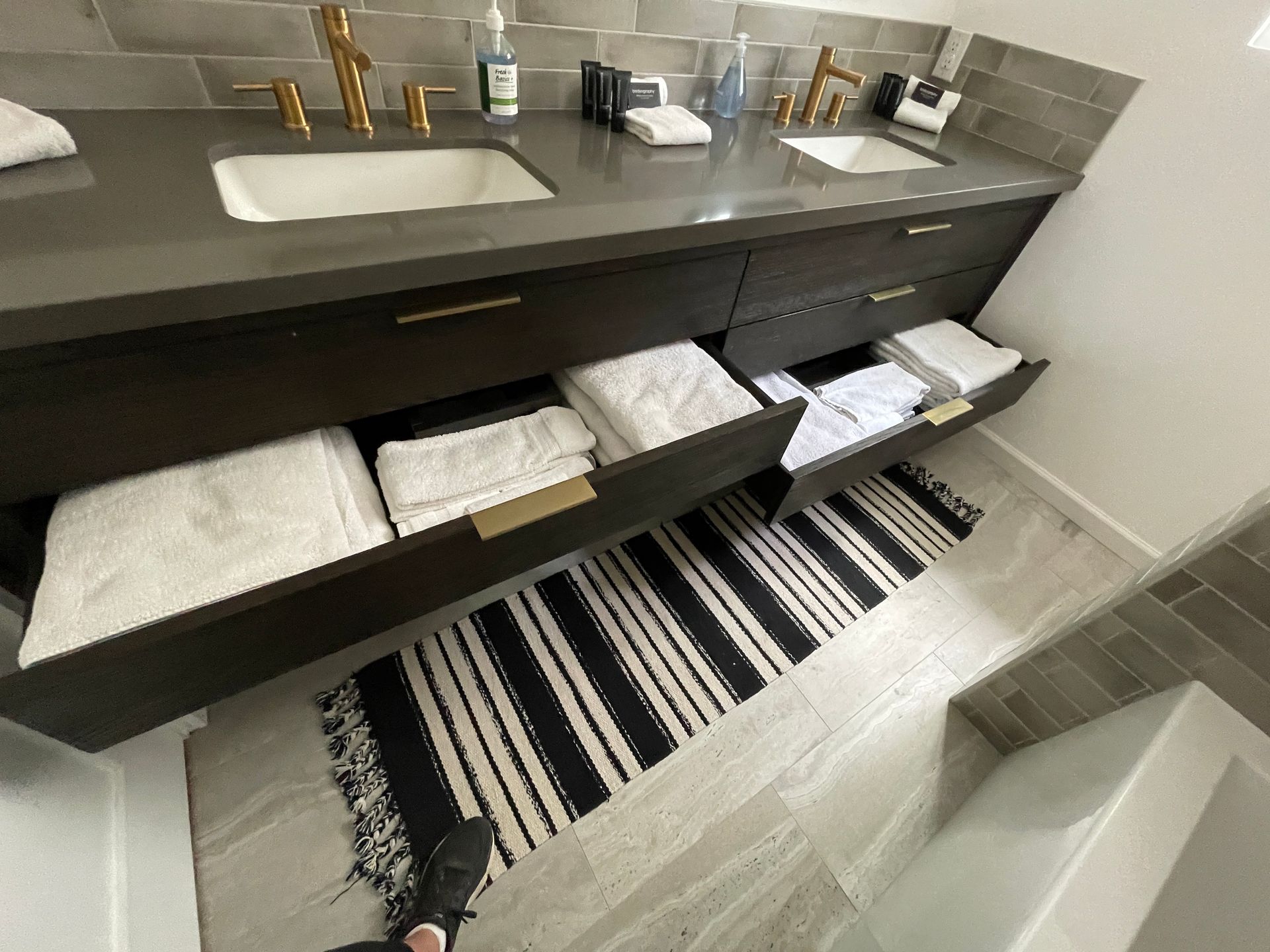A bathroom with two sinks and two drawers filled with towels.